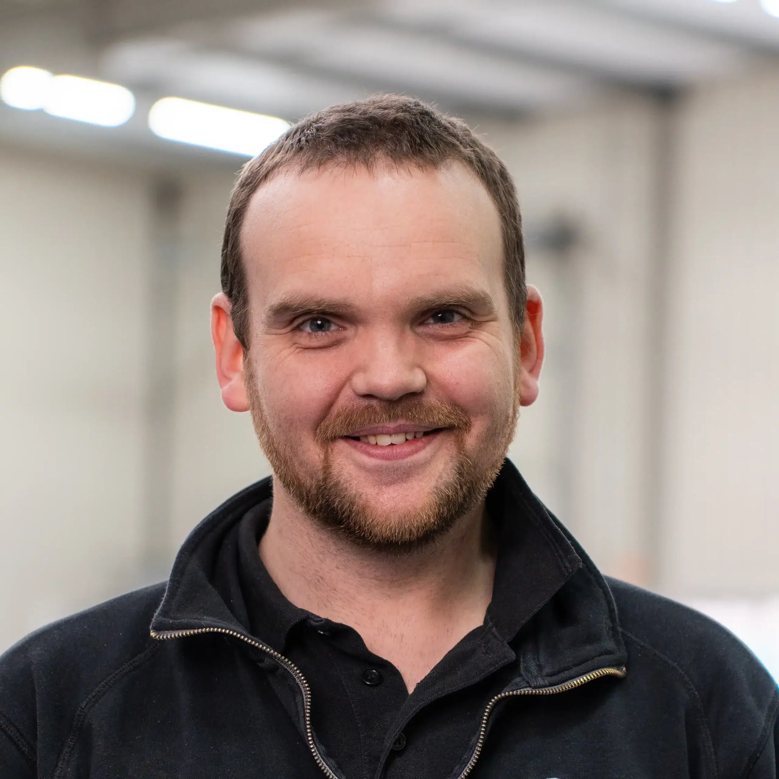 Qtents medewerker met een klein baardje en een glimlach